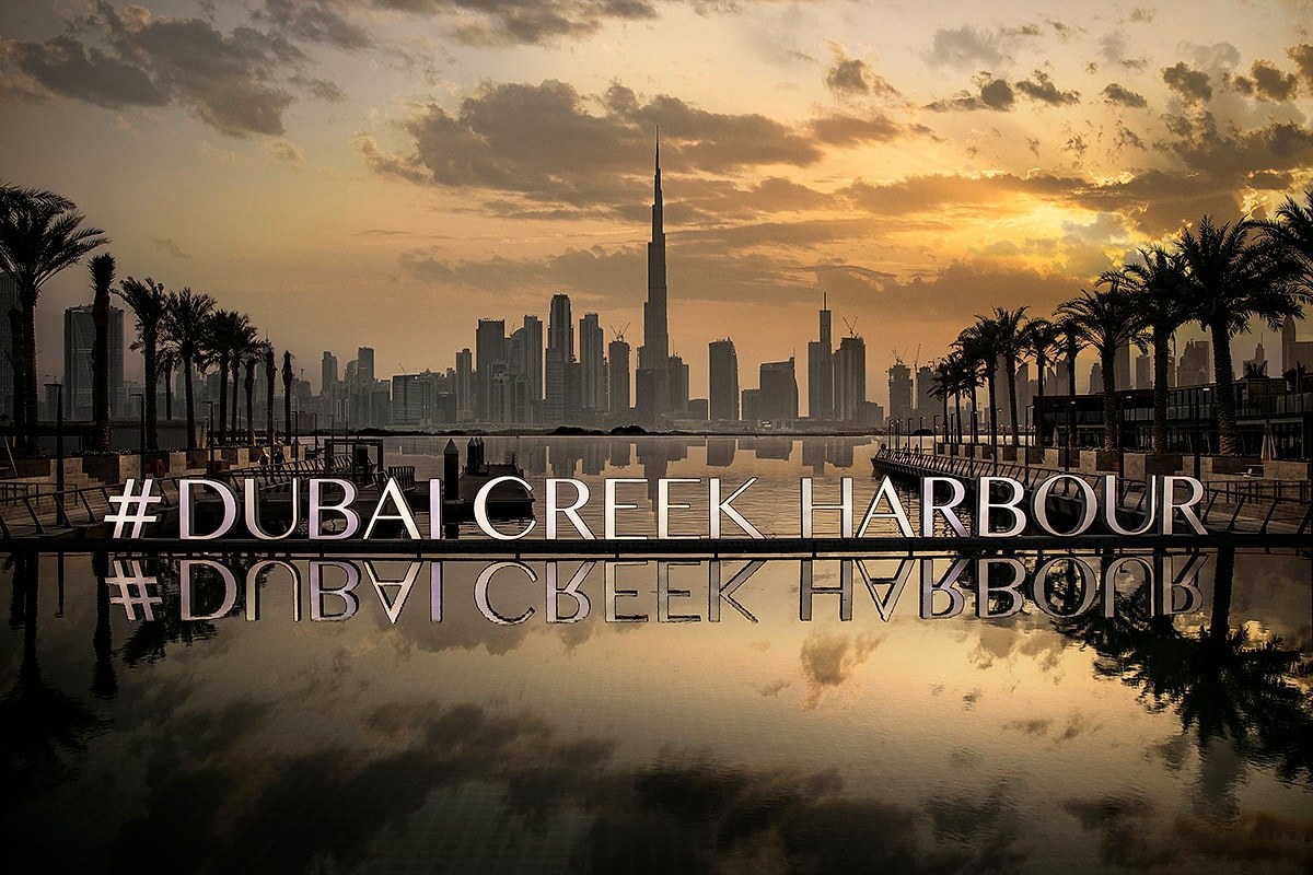 Dubai Creek Harbour promenade at sunset, with the Downtown skyline across the water